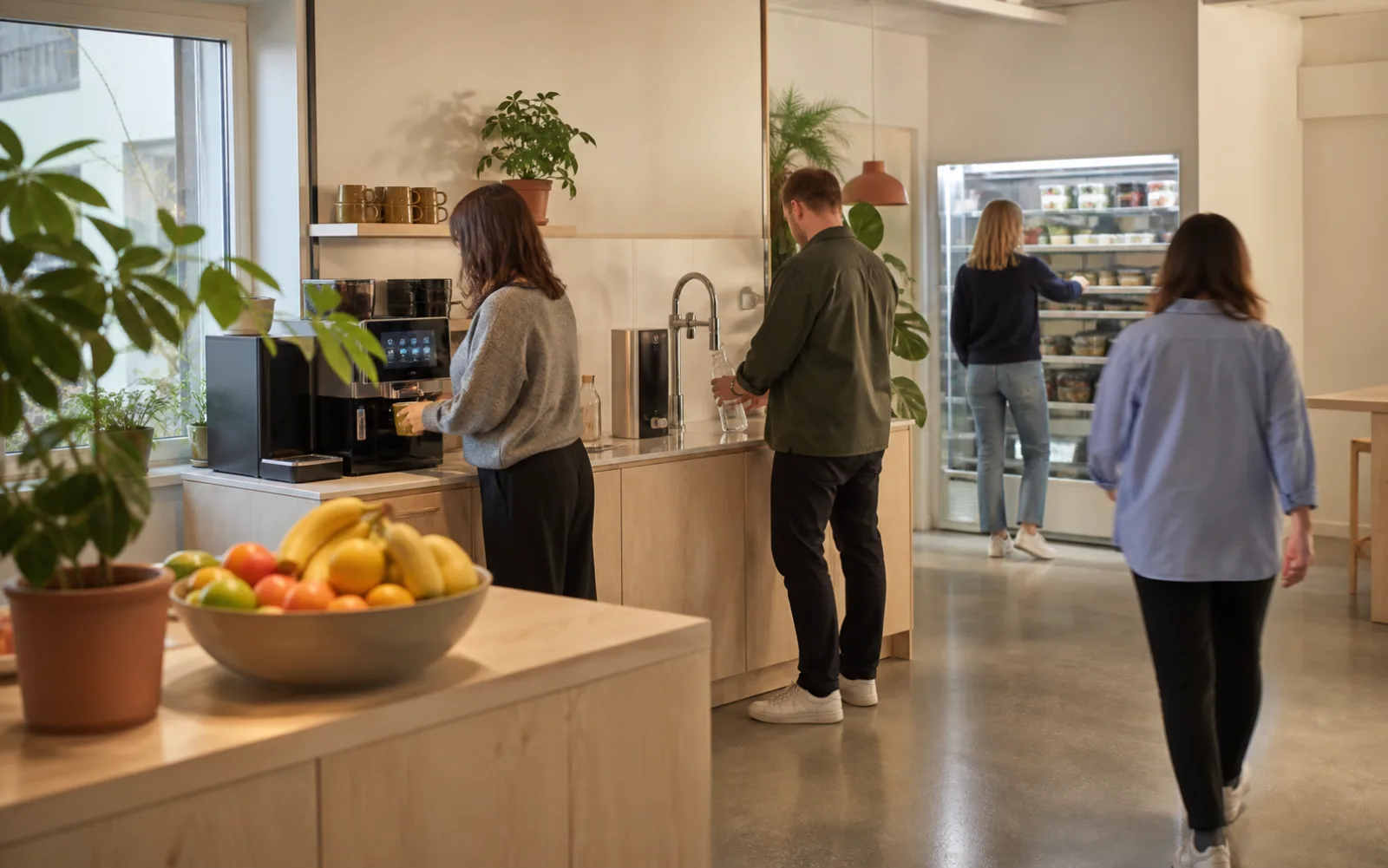 Ett personalutrymme med kaffemaskin, vattenkran, fruktskål och ett kylskåp med färdiglagad mat